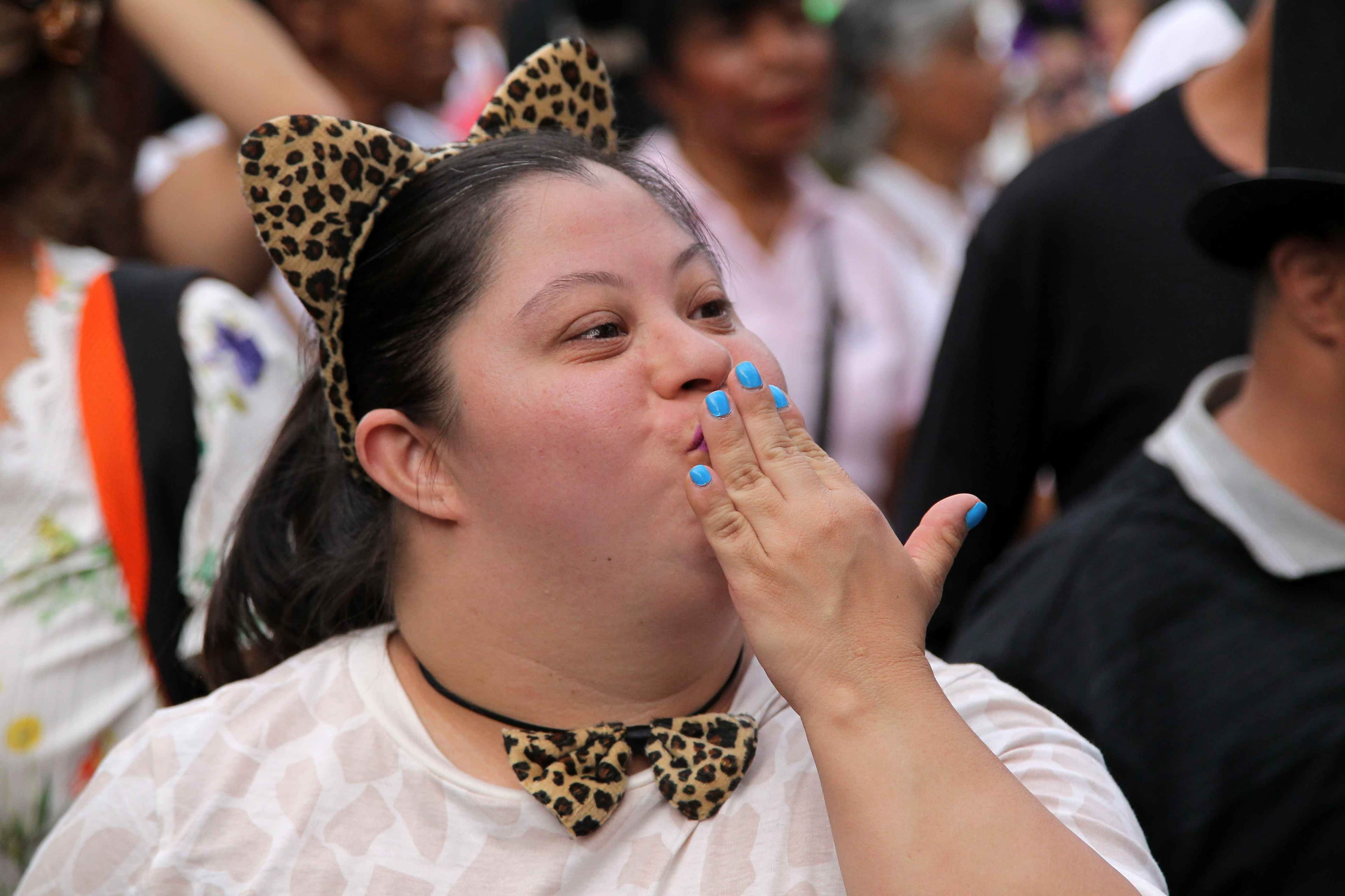 Joven en el festival de difraces con orejitas de leopardo tirando un beso. 