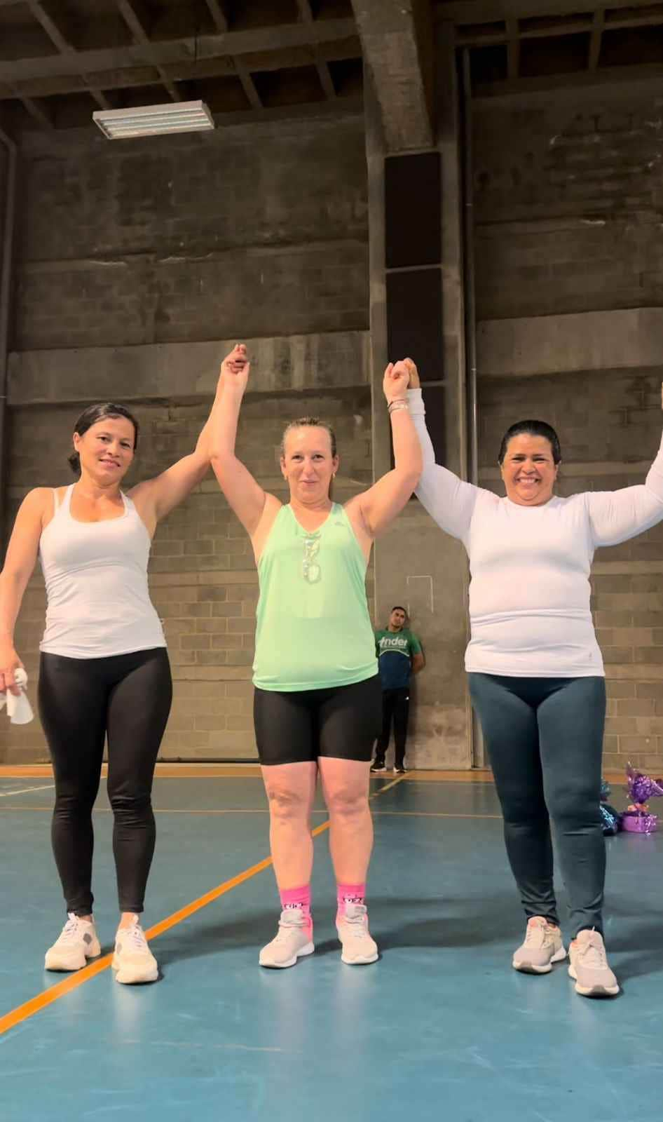 3 mujeres tomadas de las manos, alzándolas en señal de celebración y victoria